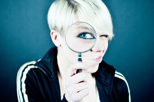 Blonde woman looking through magnifying glass