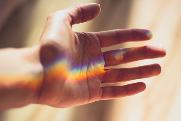 Hand reaching out with rainbow
