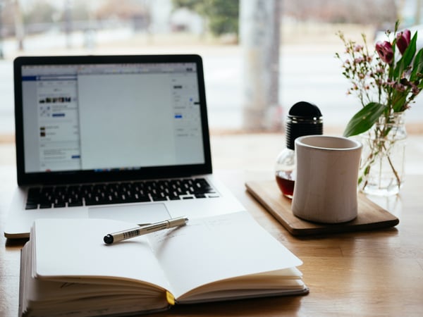 Macbook open on table with book