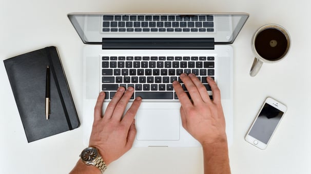 Man drinking coffee and working on laptop