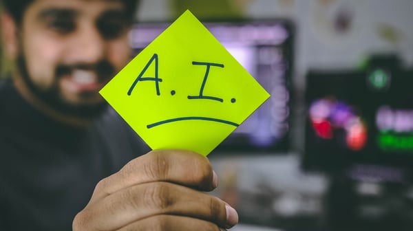 Man holding sticky note that says "AI"