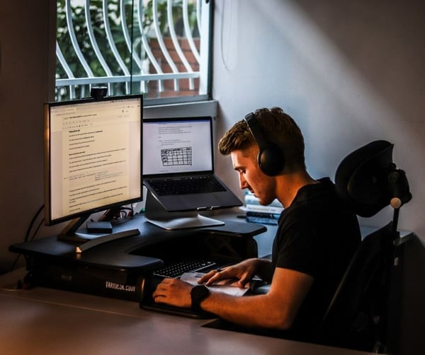 Man reading in front of two monitors