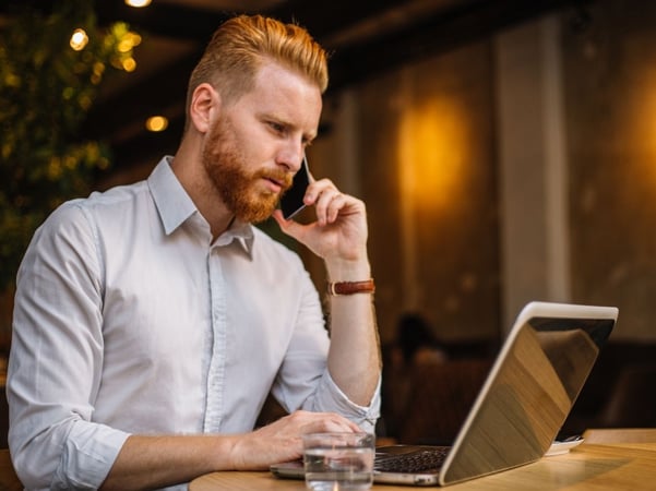 Man talking on the phone and working on laptop