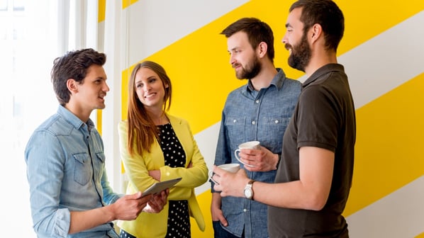 People discussing in front of yellow wall