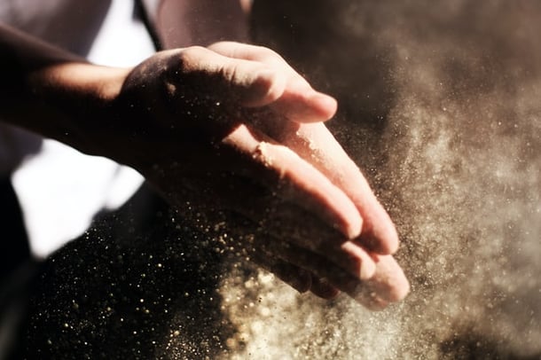 Person clapping hands with sand