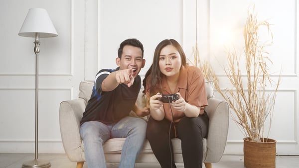 Person pointing while other person holds gaming controller