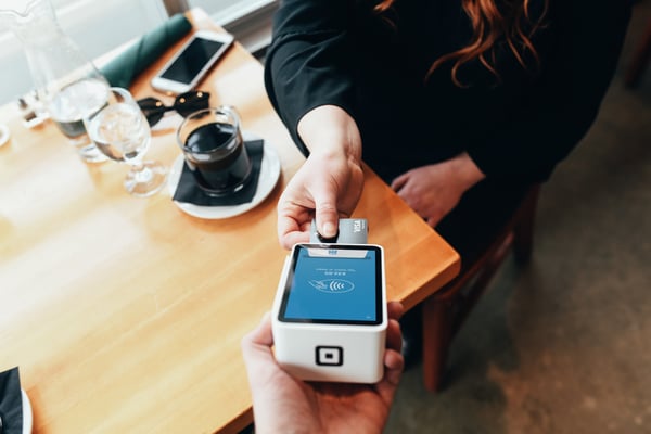 Person tapping card on swipe machine