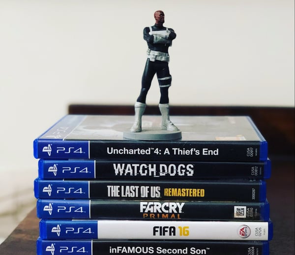 Stack of PlayStation 4 games with action figure