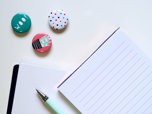 Three badges beside ruled paper