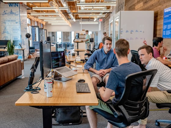 Three men sitting on a desk