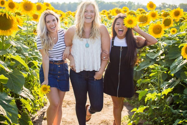 Three women standing in sunflower field