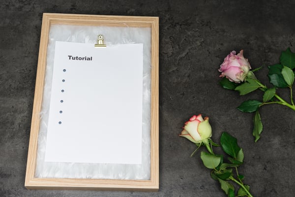 Tutorial written on white paper on clipboard with roses