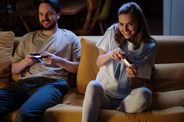 Two people playing video games on sofa