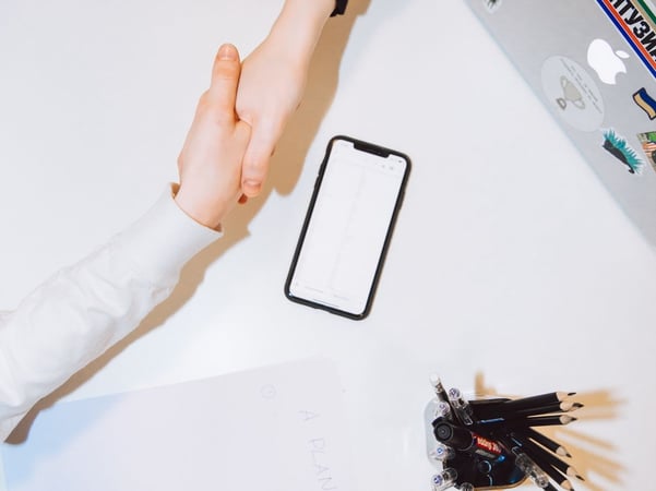 Two women shaking hands over a desk