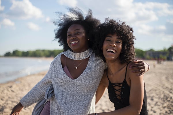 Two women standing on beach and laughing