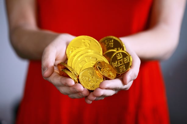 Woman dressed in red holding gold coins