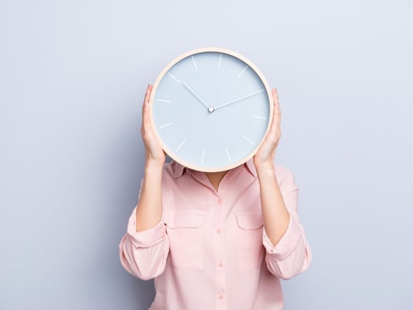 Woman keeping blue clock in front of her face