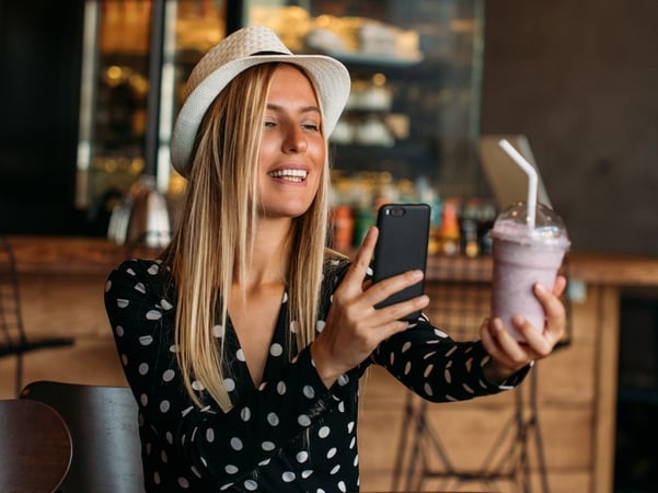 Woman photographying a pink smooothie