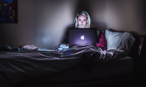 Woman sitting on bed working on laptop