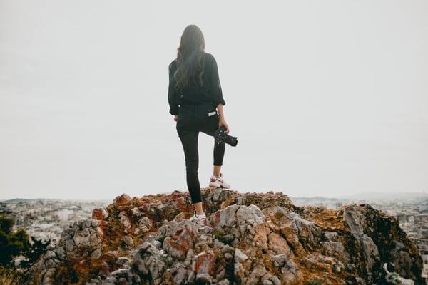 Woman standing on mountain holding camera