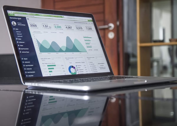 Laptop computer with statistics on glass table