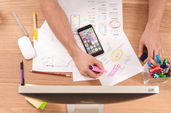 Person writing on white paper with smartphone